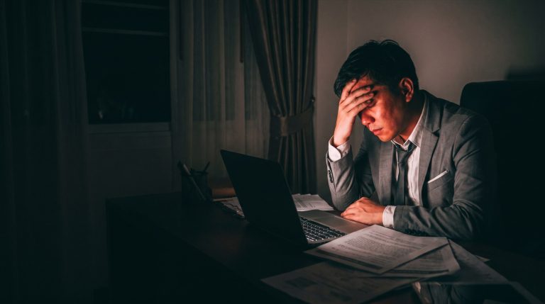 Gerente agotado trabajando de noche entre papeles